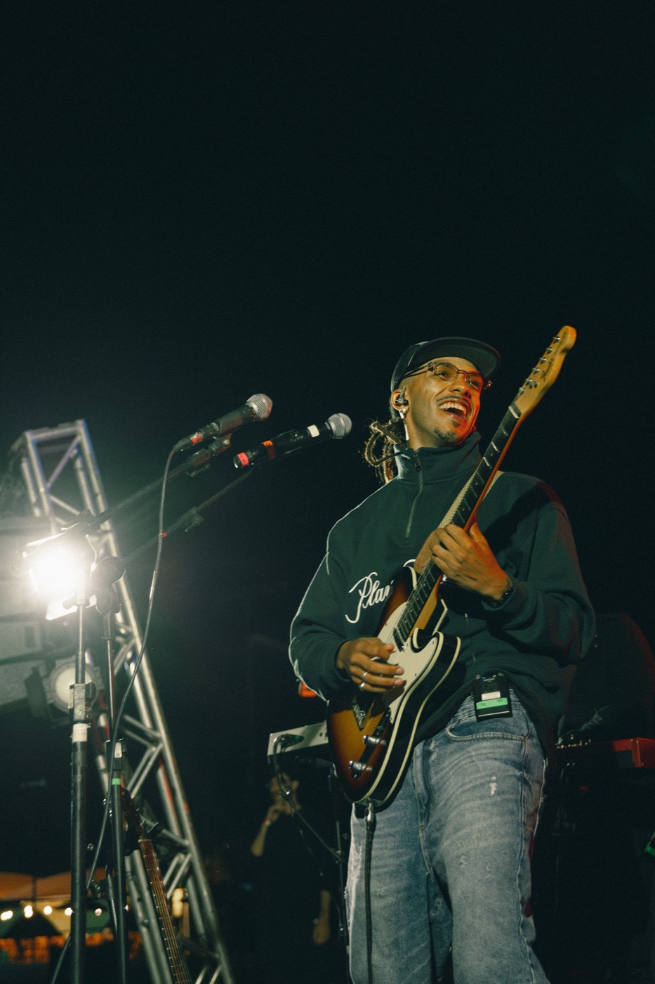 Gui tocando guitarra no palco à noite
