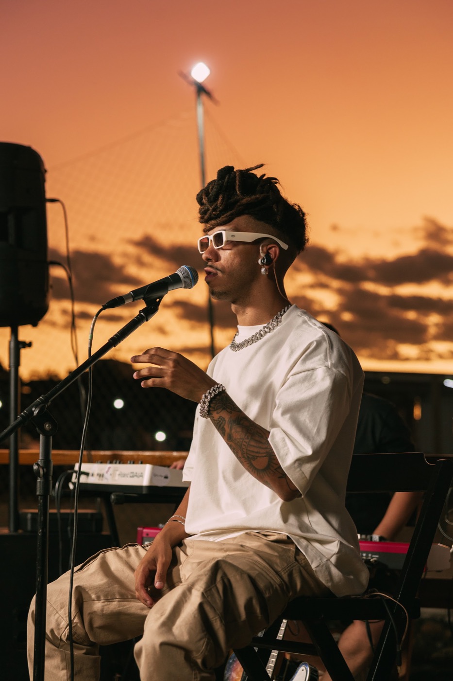 Gui tocando violão em show ao pôr do sol